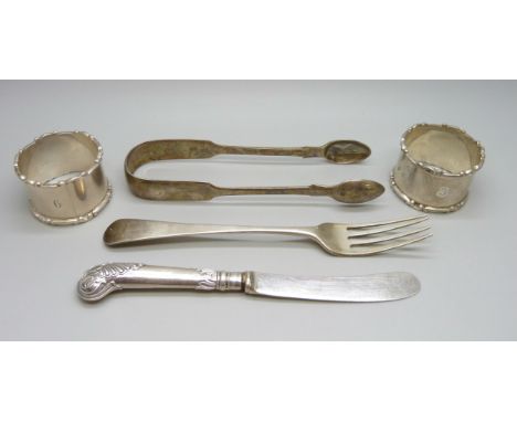 Two silver napkin rings, a pair of silver sugar tongs, a Victorian silver fork, 158g and silver handled knife