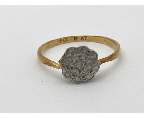 An Illusion Set Cluster Ring, of flowerhead design, between dainty tapering band stamped "18CT &amp; PLAT" (finger size K) (1