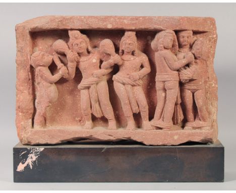 AN INDIAN MATHURA KUSHAN RED STONE CARVED PANEL, depicting kings and aprsa, with mounted base, panel 28cm x 44cm. Provenance: