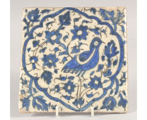 A FINE 18TH CENTURY PERSIAN BLUE AND WHITE GLAZED POTTERY TILE, painted with a bird and floral motifs, 15.5cm square.