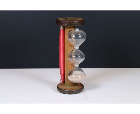 Vintage glass egg timer with three bulbous tiers held on an old mill bobbin incorporating a reel of cotton, 21cm high