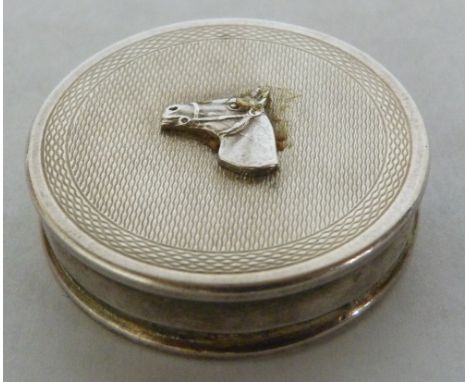 An Elizabeth II silver pillbox, the engine turned lid with applied horse head, the interior gilded. Birmingham 1963. 1½' diam