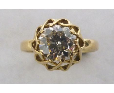 A diamond solitaire ring, the brilliant cut stone in a diaper openwork setting. In gold marked 750. The stone 8mm diam. appro