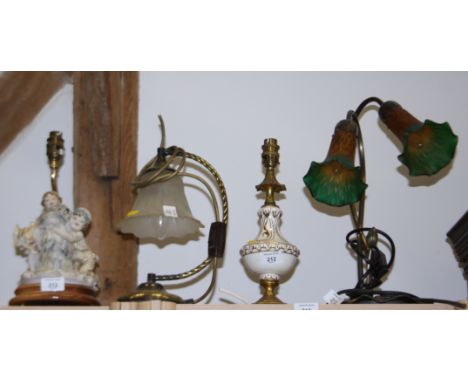 An Art Nouveau design two-light table lamp, a brass table lamp with frosted shade, a brass and ceramic table lamp and one oth