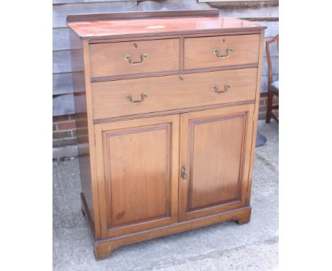 An early 20th century mahogany linen cupboard, fitted two short and one long drawer over cupboard doors, on bracket supports,