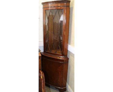 A mahogany corner display cabinet, the upper section enclosed lattice glazed door over cupboard, on bracket feet, 26" wide