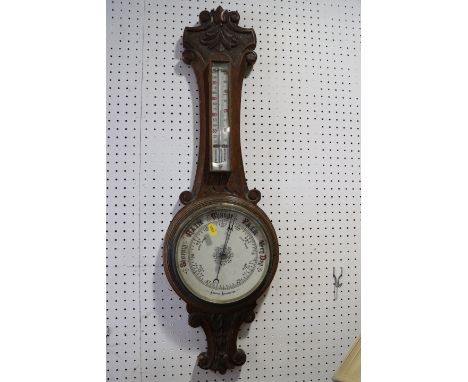 A late 19th century carved oak cased aneroid barometer and thermometer
