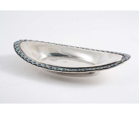 AN EDWARDIAN SMALL NAVETTE-SHAPED DISH  on button feet with a border of repeating leaf motifs, decorated in blue/green enamel
