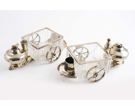 A PAIR OF VICTORIAN SMOKER'S COMPANIONS each in the form of a trolley with a vesta holder/striker, a lighter and a mounted gl