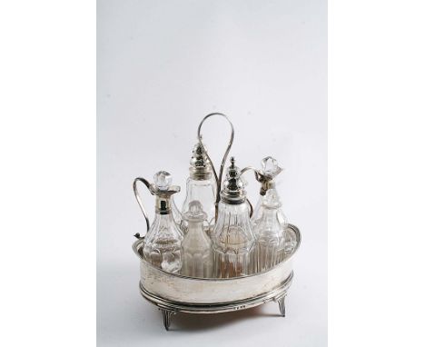 A GEORGE III BOAT-SHAPED EIGHT BOTTLE CRUET FRAME fitted with two mounted and four non-mounted, cut-glass bottles with stoppe