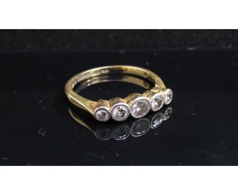 An 18ct gold platinum set five stone graduated diamond set ring in rubover setting. Size N/O, 2.9g