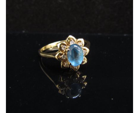 A gold ring the central blue cabochon framed by diamonds. Size Q, stamped 18k, 3.3g