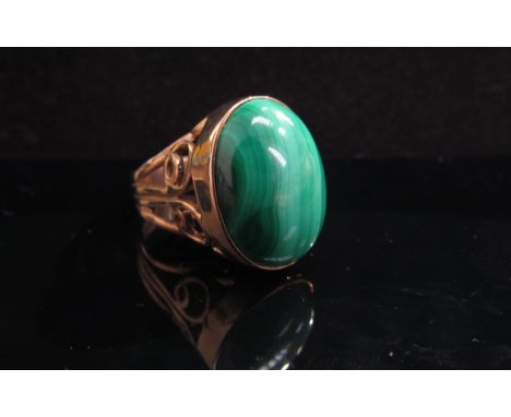 A 9ct gold ring set with large malachite oval in open scroll setting. Size O, 9.8g