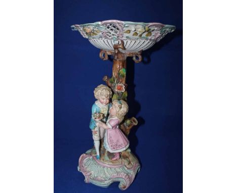 20TH CENTURY GERMAN CERAMIC TABLE CENTREPIECEin the style of Dresden and Meissen, modelled as a boy and a girl embracing with