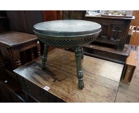 An Eastern brass travelling stool, the circular top with stylized floral decoration above a pierced frieze and detachable thr