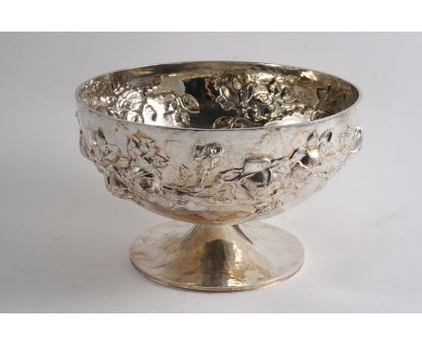 AN ARTS & CRAFTS ROSE BOWL on a spreading foot, embossed around the sides with trailing roses against a hammered ground & sig