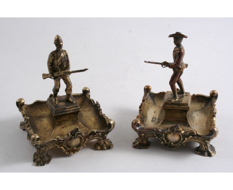 A PAIR OF UNUSUAL EDWARDIAN SILVERGILT SALTS cast with decorative borders and central regimental figure finials, each in the 