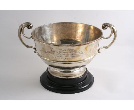 A SHALLOW CIRCULAR TROPHY CUP  with two harp-shaped handles, a moulded girdle & a small presentation inscription, turned ebon