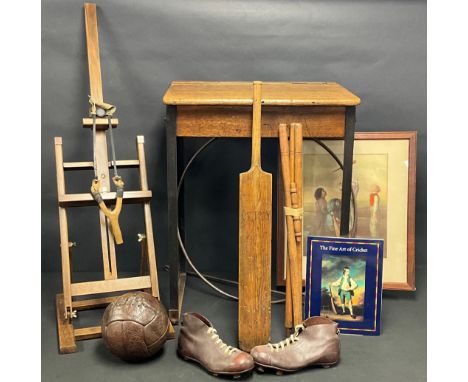 An early 20th century brown leather football, child's football boots, cricket bat and stumps with cricket print, catapult, a 