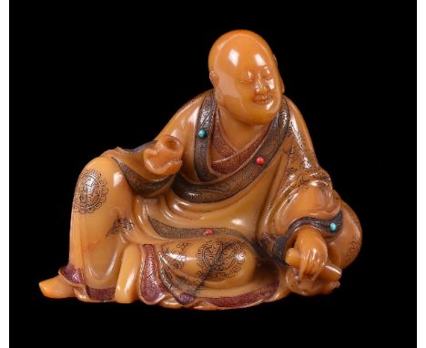 A Chinese soapstone model of a Luohan, his corpulent body draped in long flowing monastic robes opening at the chest and intr