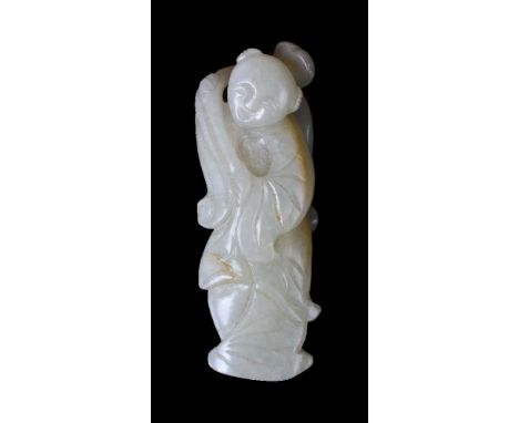 A Chinese celadon and russet jade carving of a boy, Qing Dynasty, the boy holding the stem of a large lotus spray over his sh