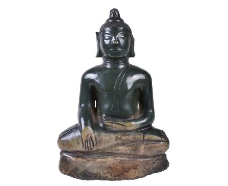 A Burmese jade Buddha, late 18th or 19th century, seated in vajrasana on roughly hewn base, his right hand in bhumisparshamud