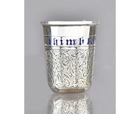 A silver spirit tot, modelled as a thimble, having scroll engraved decoration and detailed in blue enamel 'Just a thimbleful'