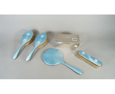 A lady's silver and pale blue enamelled four piece part dressing set, comprising; a hand mirror, two hairbrushes and one clot