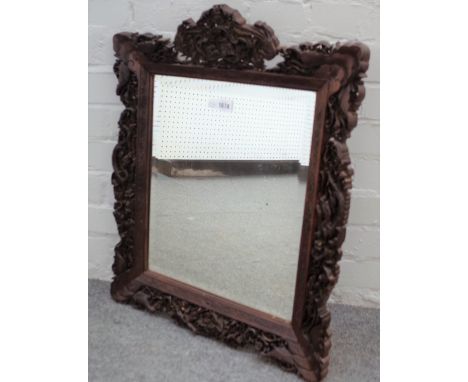 A Chinese hardwood mirror with extensively carved frame depicting hunting scenes, dragons and wildlife, 50cm wide x 64cm high