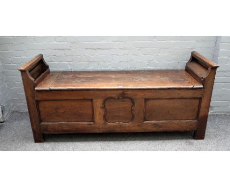 A 17th century oak box settle with pair of raised candle box ends over plank lift top and triple panel front, 180cm wide x 81