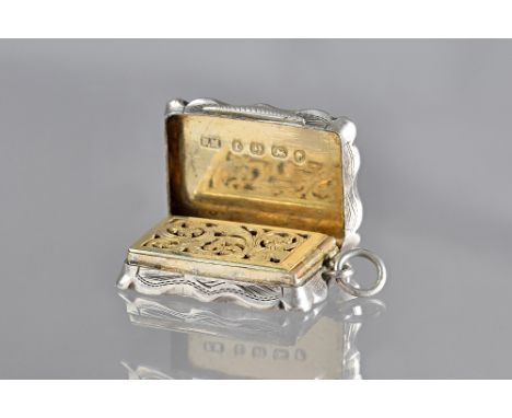 A Victorian silver shaped rectangular vinaigrette, with a scroll pierced and engraved grille, the exterior engine turned and 