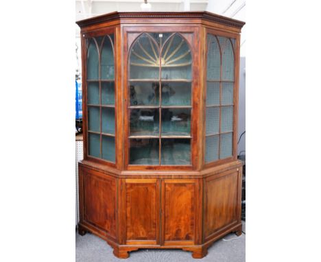 An early 19th century Irish mahogany display cabinet/cupboard, the Gothic arch glazed top with swept sides over lower panel c