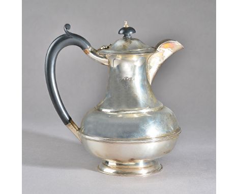 A silver hot water jug, of baluster form, raised on a circular foot, with a black handle and with a black finial, Birmingham 