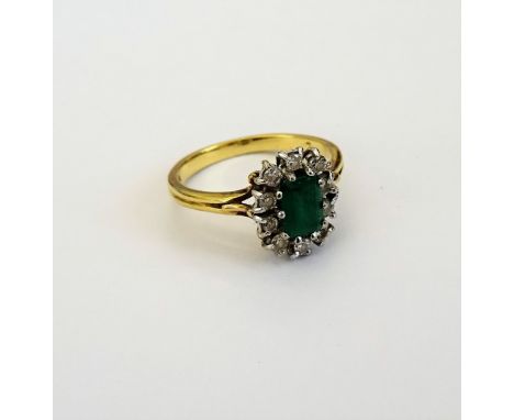 An 18ct gold, emerald and diamond cluster ring, claw set with the rectangular step cut emerald at the centre, in a surround o