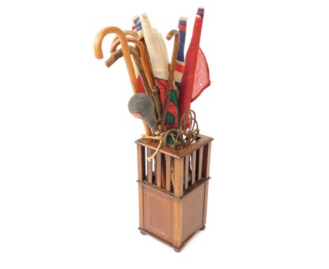 An Edwardian mahogany and line inlaid square stick stand, containing various walking sticks, beaters and flags, together with