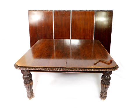 A Victorian oak wind-out dining table, with four additional leaves, the top with leaf carved edging, raised on carved and tur