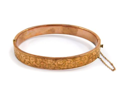 A 9ct gold bangle, with engraved foliate decoration, on a snap clasp with safety chain as fitted, 9.2g.
