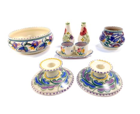 A group of Poole Pottery, traditionally painted with flowers, comprising a pair of candlesticks, bowl, ogee shaped vase, and 