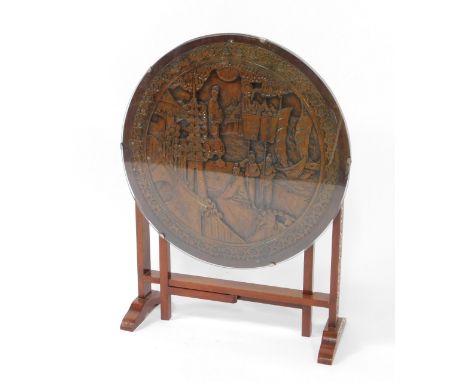A Chinese hardwood tilt top gate leg occasional table, the circular top carved with figures, pagodas and a landscape within a