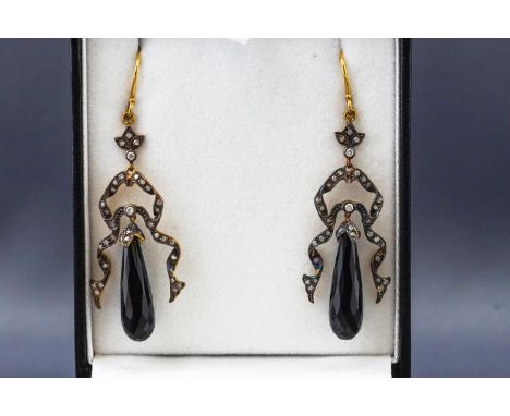 A yellow and white metal pair of drop earrings each having an elongated faceted teardrop jet (untested) and single cut diamon