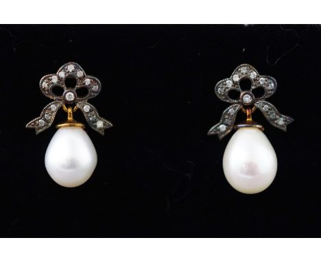 A yellow and white metal pair of drop earrings each having a freshwater pearl and set with single cut diamonds to a bow desig