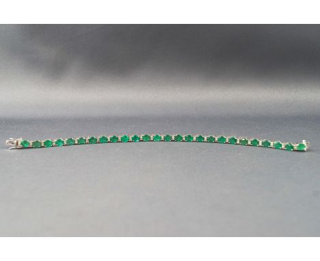 A white metal line bracelet set with twenty six oval faceted cut emeralds inter spaced with single cut diamond pairs. Estimat
