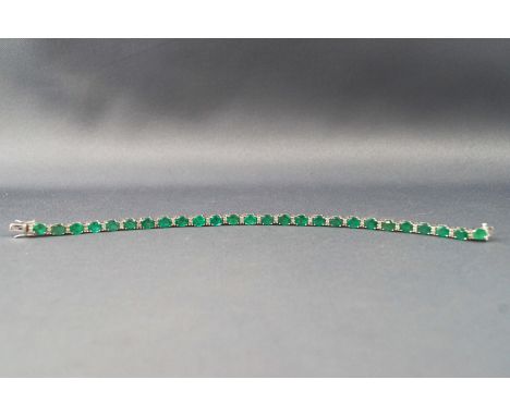 A white metal line bracelet set with twenty six oval faceted cut emeralds inter spaced with single cut diamond pairs. Estimat