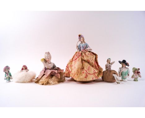 A group of seven porcelain half doll pin cushion ladies, four made up on fabric bases