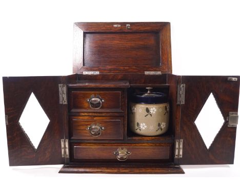 An oak smoker's cabinet with two lozenge glazed doors and lifting top, opening to reveal a fitted interior with pipe rack, tw