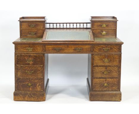 An oak Dickens style desk, the rectangular top with two end towers, each set two drawers with blind galleries centring a shel