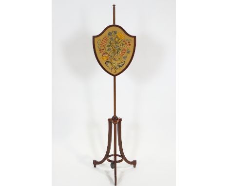 A mahogany pole screen in the 18th century style with shield shaped weighted embroidery on a tripod base, 150cm high