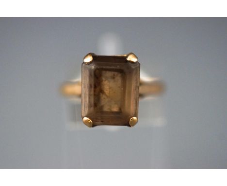 A yellow metal single stone ring set with a rectangular faceted cut smokey quartz. Size: M  Hallmarked 9ct gold, London. 3.7 