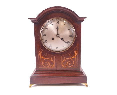 An early 20th century eight day mantel clock, with a corniced domed top over a round silvered Roman dial, the casae front inl