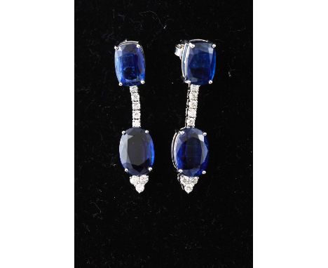 A white metal pair of drop earrings. Each set with two cushion faceted cut Kyanite and eight round brilliant cut diamonds. Es